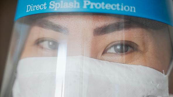 A close up of a healthcare worker wearing a mask and visor.