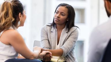 Two patients holding hands during a counselling session.