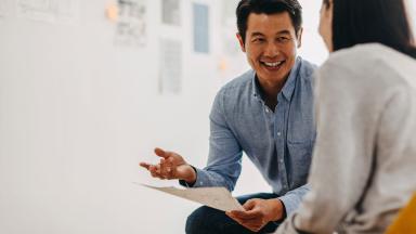 Two officer workers laughing during a meeting.