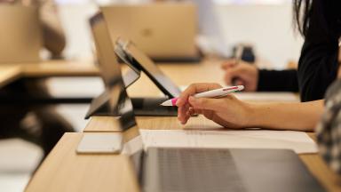 An office worker writing on a pad next to a laptop.