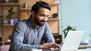 person in office looking at laptop and smiling
