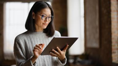 person standing in office reading electronic tablet