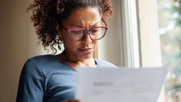 A women looks at a piece of paper with a concerned expression.