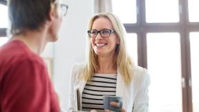 Two office workers chat over coffee.