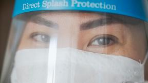 A close up of a healthcare worker wearing a mask and visor.