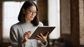 person standing in office reading electronic tablet
