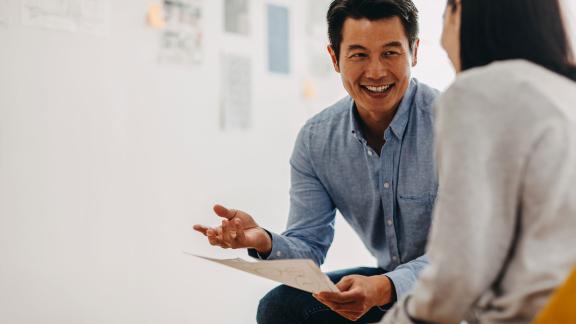Two officer workers laughing during a meeting.