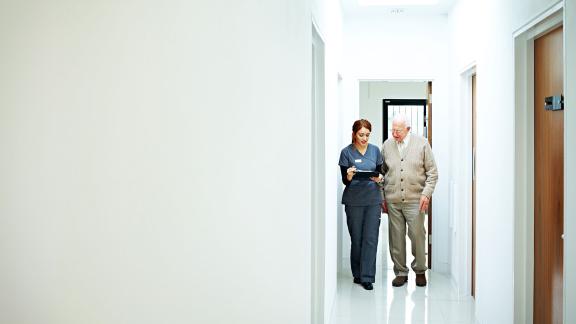A nurse and a patient walking down a corridor.