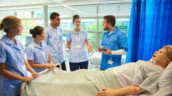 Student nurses gathered around a medical dummy.