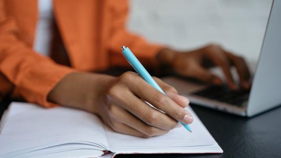 A homeworker writing on a laptop.