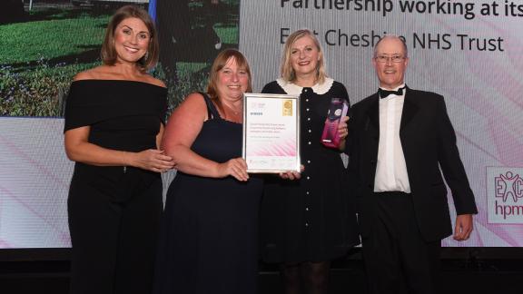 The winners of the HPMA standing on a stage dresses in formal wear, holding a certificate and a prize.