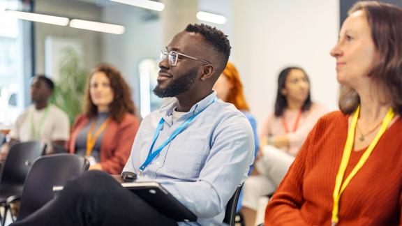 diverse conference attendees smiling while listening to presentation