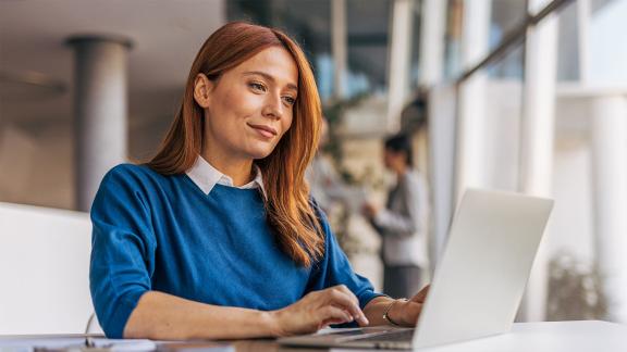 person sitting in office and smiling while looking at laptop