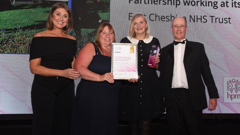 The winners of the HPMA standing on a stage dresses in formal wear, holding a certificate and a prize.