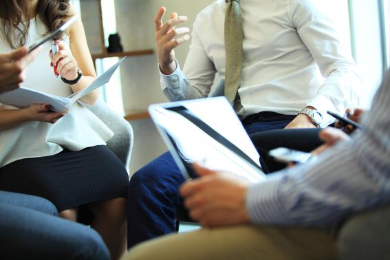 A group meeting, with tablets, viewed at waist height.